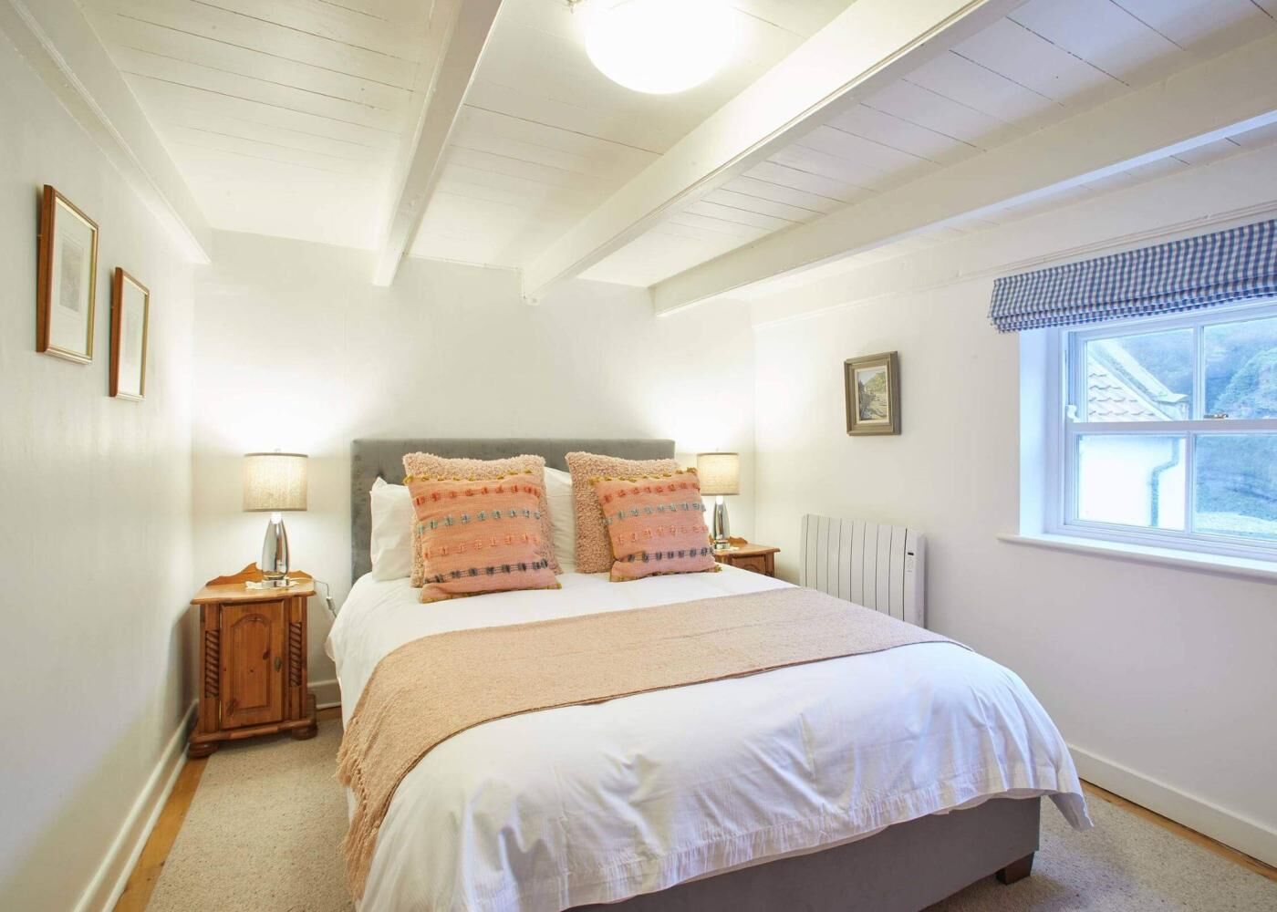 Une chambre à coucher avec un lit, deux tables de chevet, une fenêtre donnant sur un paysage agréable et un radiateur.