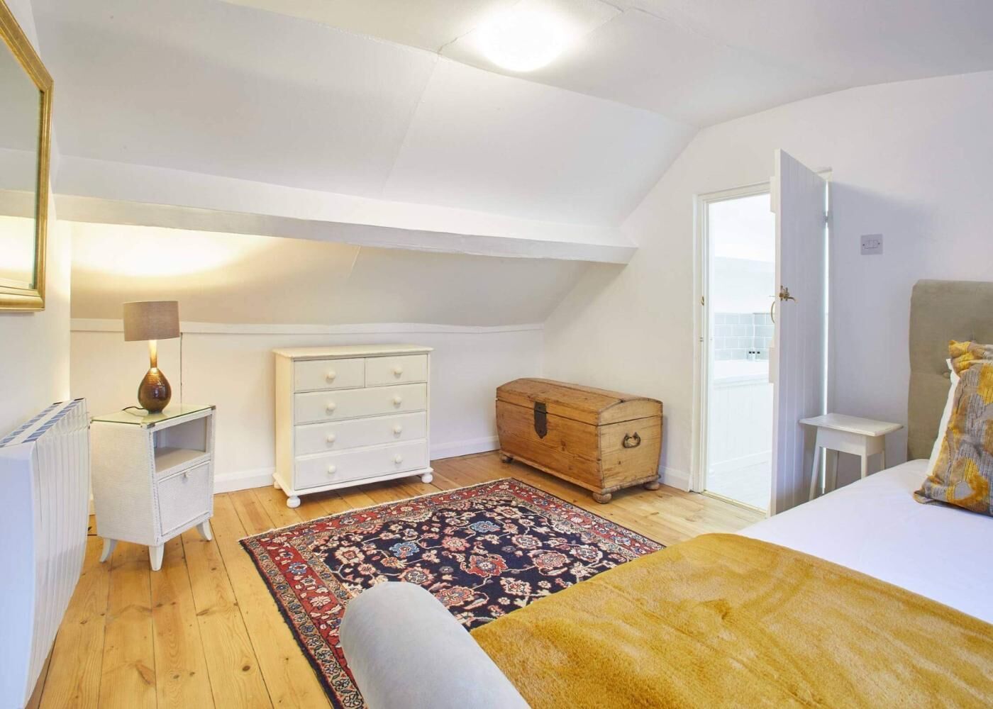 Une chambre à coucher avec un lit, une commode, une commode à tiroirs, une lampe et un tapis.