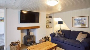 A cozy living room with a wooden sofa, a television mounted on the wall, a fireplace, and a wooden coffee table. - 3 Bed in Staithes (oc-g29738) (Staithes)