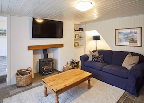 Ein gemütliches Wohnzimmer mit einem Holzsofa, einem an der Wand befestigten Fernseher, einem Kamin und einem Holztisch.