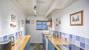 A kitchen with wooden countertops, blue cabinets, and patterned backsplash tiles. - 3 Bed in Staithes (oc-g29738) (Staithes)