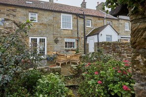 A stone building with a garden patio, stone walls, and a white door. - 4 Bed in Egton (oc-a29734) (Egton)
