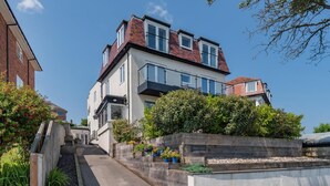 Une maison moderne à deux étages, dotée d’un toit plat, de grandes fenêtres et d’un jardin bien entretenu.