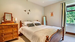 Ein Schlafzimmer mit Bett, Kommode und einem Fenster mit Vorhängen.