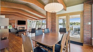 Un espace intérieur spacieux avec une grande table et des chaises en bois, une cheminée et un téléviseur.