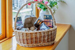 A wicker basket filled with chocolate, eggs, and a chocolate bar on a wooden ledge by a window. - 2 Bed in Crugybar (oc-t29740) (Cynwyl Gaeo)