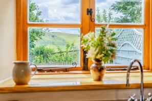 A kitchen with a window view of a green landscape and a wooden fence. - 2 Bed in Crugybar (oc-t29740) (Cynwyl Gaeo)