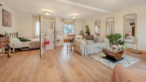 Uma sala de estar ampla, com piso de madeira, um sofá, uma mesa de centro e um espaço para refeições.