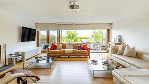 Un salon spacieux avec un grand canapé, une table basse et un téléviseur fixé au mur.