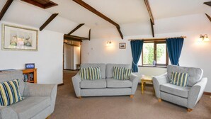 A cozy living room with two grey sofas, a small wooden table, and a bookshelf. - 2 Bed in Padstow (oc-w3658) (Treyarnon Bay)