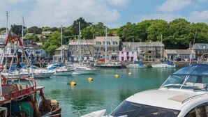 A marina with boats docked, a white car in the foreground, and buildings in the background. - 3 Bed in St. Ervan (oc-t29660) (Saint Ervan)