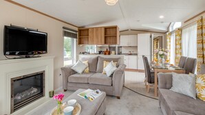 Een moderne woonkamer met een open haard, een televisie en een eethoek met gele gordijnen.
