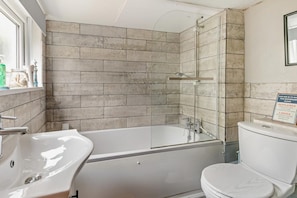 Een badkamer met een bad, een wastafel en een toilet.