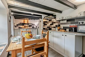 A modern kitchen with white cabinets, a wooden dining table, and a breakfast setup.