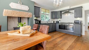 Una cocina moderna con armarios grises, una mesa de comedor de madera y una lámpara de araña.