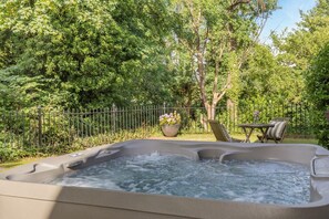 A hot tub surrounded by a lush garden with a fence, a table with chairs, and a potted plant. - 5 Bed in Belper (oc-b29775) (Belper)