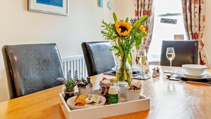 A dining table set with a vase of sunflowers, a bottle of milk, and a tray of snacks. - 1 Bed in Beadnell (oc-l29758) (Beadnell)