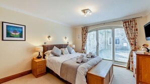 A bedroom with a bed, bedside tables, a TV, and a window with curtains. - 1 Bed in Beadnell (oc-l29758) (Beadnell)