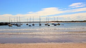 A beach with several sailboats anchored in the water, a sandy shore, and a clear sky. - 1 Bed in Beadnell (oc-l29758) (Beadnell)