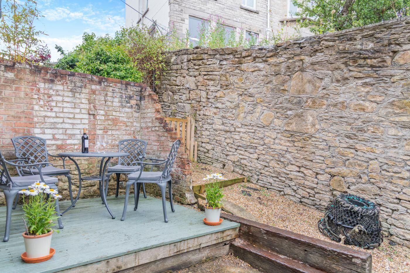 Eine Terrasse mit einer Steinmauer, einem Tisch und Stühlen.