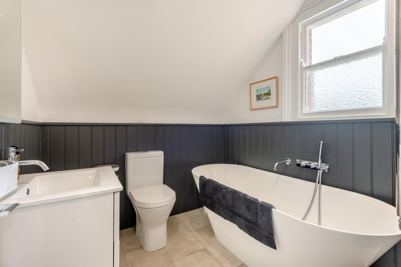 Et badeværelse med et hvidt badekar, et hvidt toilet og en vask.