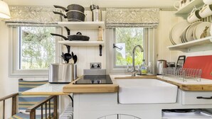 Een kleine keuken met een spoelbak, fornuis en opbergkastjes.