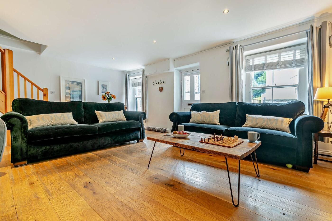 A living room with two dark green sofas, a wooden coffee table, and a chessboard.