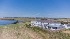 A coastal house with a large patio, a view of the sea, and a hilly landscape in the background. - 2 Bed in Langton Herring (oc-r29848) (Langton Herring)
