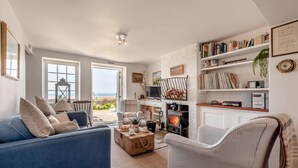 A living room with a blue sofa, a fireplace, and a bookshelf. - 2 Bed in Langton Herring (oc-r29848) (Langton Herring)