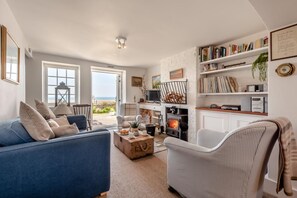 Una sala de estar con sofá azul, chimenea y estantería.