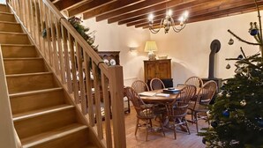 Una escalera de madera con barandilla lleva a un comedor con una mesa redonda y sillas.