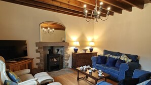 Una sala de estar acogedora con chimenea de piedra, televisor, sofá y una mesa de centro.