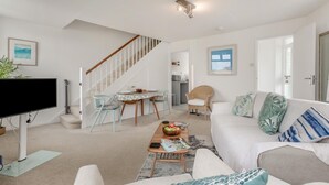 A living room with a sofa, coffee table, and a TV. There's a staircase leading to another room. - 1 Bed in St. Ives (oc-p29852) (St Ives)
