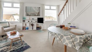 A modern living room with a sofa, coffee table, and dining table set for breakfast. - 1 Bed in St. Ives (oc-p29852) (St Ives)