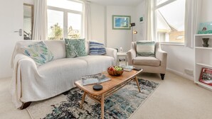 A living room with a sofa, armchair, coffee table, and a bookshelf. - 1 Bed in St. Ives (oc-p29852) (St Ives)