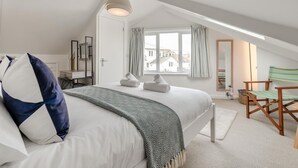 A bedroom with a bed, a desk, a chair, a window with curtains, and a ceiling light. - 1 Bed in St. Ives (oc-p29852) (St Ives)