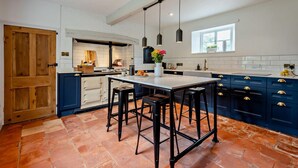 A kitchen with a central island, bar stools, and blue cabinetry.