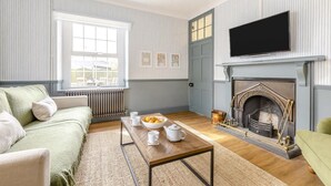 Ein Wohnzimmer mit einer Couch, einem Couchtisch, einem Kamin und einem Fernseher.