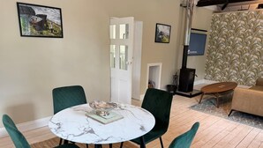 A dining area with a round table, green upholstered chairs, a marble top, and a silver serving tray. - 1 Bed in Northrepps (oc-m29800) (Crossdale Street)