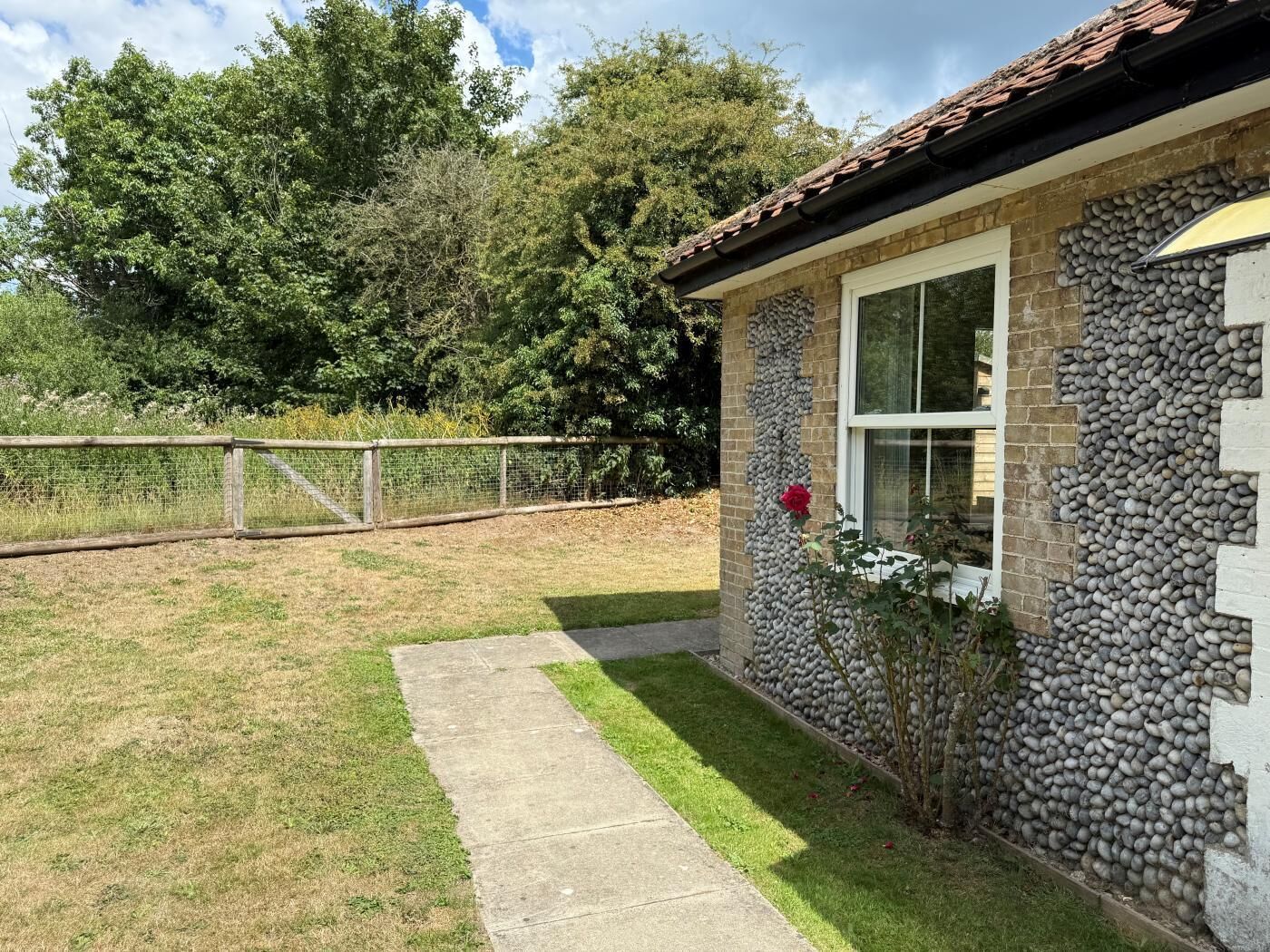 A house with a stone exterior, a window, and a small garden area with a pathway.