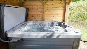 A hot tub with a metallic exterior, set in a wooden structure with a covered roof. - 1 Bed in Northrepps (oc-m29800) (Crossdale Street)