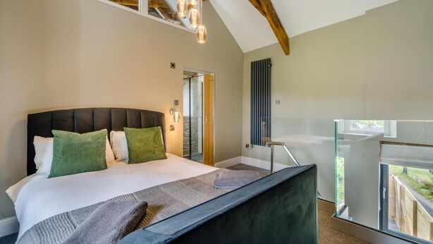 A bedroom with a large bed, a glass balcony, and a view of the outdoors. - 1 Bed in Tebay (oc-m29886) (Mount Pleasant)