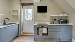 A compact kitchen with grey cabinets, a black sink, a built-in microwave, and a small window. - 1 Bed in Tebay (oc-m29886) (Mount Pleasant)