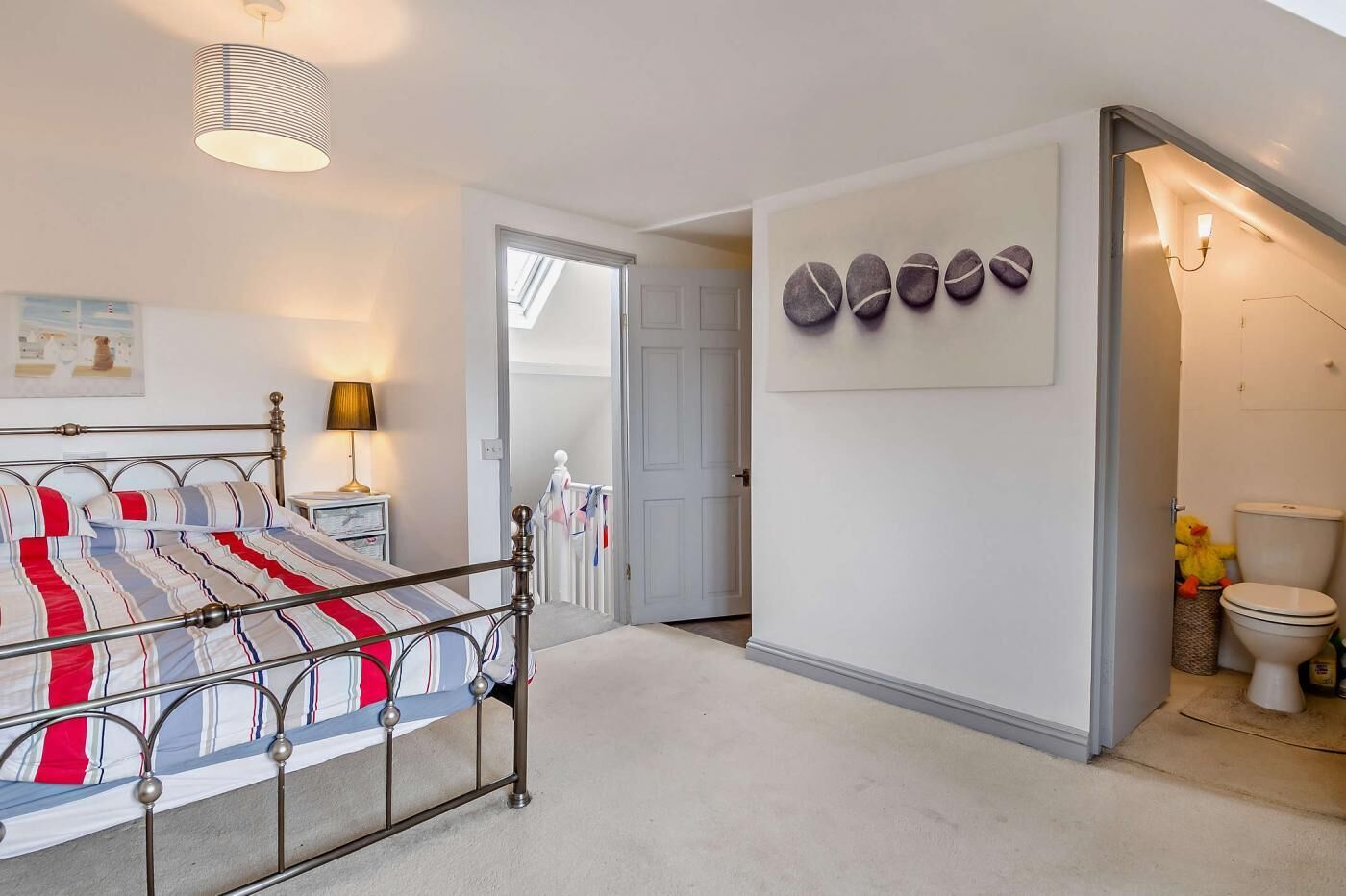 A bedroom with a metal bed frame, a bedside lamp, and a wall-mounted artwork.