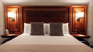 Ein Hotelzimmer mit einem großen Bett, zwei Nachttischen mit Lampen und einem Holzkopfstück.