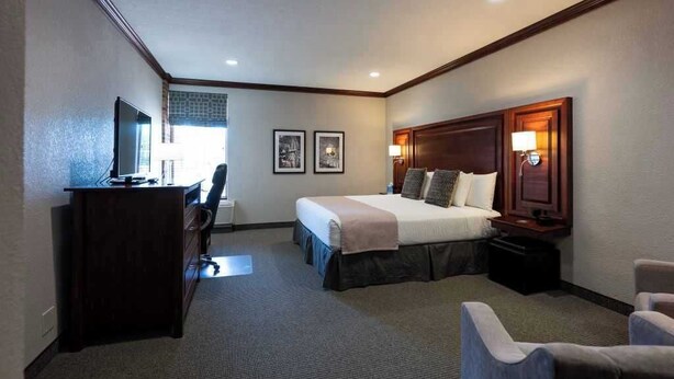 Ein Hotelzimmer mit Bett, Schreibtisch, Stuhl und Fernseher.