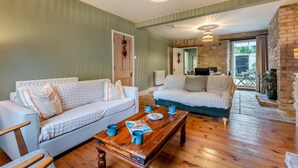 A cozy living room with two checkered sofas, a wooden coffee table, and a stone fireplace. - 3 Bed in Swanage (oc-n29755) (Swanage)