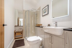 Une salle de bain moderne avec une douche à parois de verre, un lavabo blanc et des toilettes.