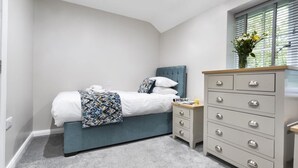 Un dormitorio con cama, mesita de noche, cómoda y una ventana con persianas.