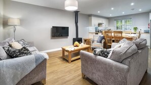 Una sala moderna con un conjunto de sofá, una mesa de centro y un televisor. Cuenta con una zona de cocina con una mesa de comedor y sillas.